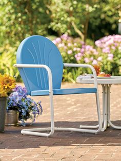 two blue chairs sitting on top of a brick patio next to a small table and flowers