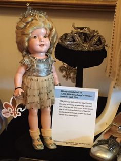 a doll with a tiara next to a sign