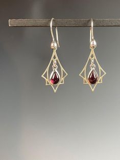 "Art Deco lovers rejoice! Here are red Garnet earrings in Sterling silver! So often we see Art Deco designs that are only red and gold but I also make Garnet and silver jewelry in Art Deco inspired designs.  These sweet earrings are lightweight and easy to wear. The deep red Garnet gemstones smooth cabachons that are bezel set in Sterling silver that dangle freely in a Sterling Art Deco charm. They hang 1.5 inches on Sterling silver ear wires with a sterling accent. These also make a wonderful g Formal Dangle Garnet Earrings, Formal Garnet Dangle Earrings, Elegant Garnet Teardrop Earrings, Elegant Garnet Earrings, Garnet Drop Earrings As Gift, Garnet Drop Earrings With Ear Wire, Garnet Earrings For Gift, Garnet Earrings For Pierced Ears As Gift, Garnet Earrings For Pierced Ears