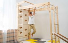 a man standing on top of a bunk bed in a room with yellow and white rugs