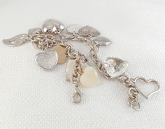 This etched silver tone oval links hearts charm bracelet measures 8 inches, but may wear smaller due to all the charms; the lobster claw clasp fits all of the links, so you adjust it shorter measures 8 inches end to end, but you can shorten it if necessary has 14 various vintage charms, most of which are hearts charms are enamel, rhinestone, mother of pearl, resin, etc. is in excellent condition perfect for a best friend, a girlfriend, mom, or yourself! Excellent Valentine gift! If you love vint Heart Shaped Charm Bracelet With Lobster Clasp For Anniversary, Silver Heart Bracelets With Dangling Charms, Silver Metal Heart Bracelet With Charms, Metal Heart Bracelet With Lobster Clasp For Anniversary, Vintage Heart Charm Bracelet For Gift, Metal Charm Bracelet With Lobster Clasp For Anniversary, Silver Heart Charm In Metal, Anniversary Metal Heart Bracelet With Lobster Clasp, Metal Charm Bracelet With Lobster Clasp For Valentine's Day