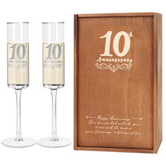 two champagne flutes sitting in front of a wooden box with the number ten anniversary written on it