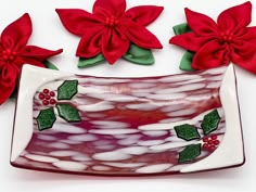 a decorative glass dish with red flowers and green leaves