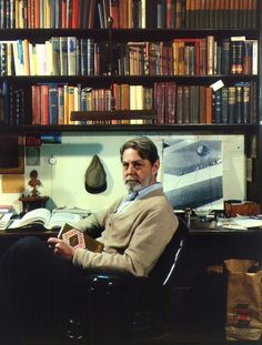 a man sitting in a chair with his feet up on the desk next to bookshelves