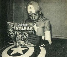 a man reading a comic book with captain america written on it