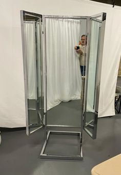 a woman taking a selfie in front of a large mirror with curtains behind her