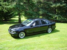 a black car parked on top of a lush green field