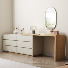 a white dresser sitting next to a mirror on top of a wooden floor in a room