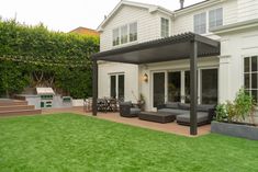 an outdoor living area with couches, table and grill in front of the house