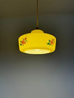 a yellow hanging light with flowers painted on it