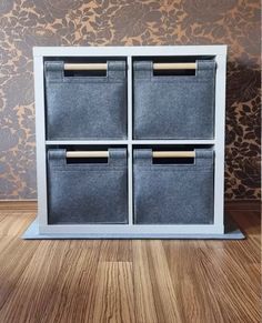 three bins with handles are sitting on the floor in front of a wallpapered wall