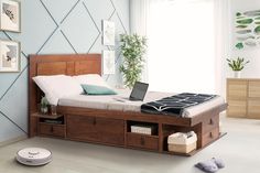 a bed with a laptop on top of it next to a dresser and other items