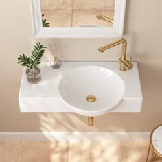 a white sink sitting under a mirror next to a table with a potted plant