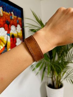 Beautiful Guatemalan authentic leather bracelet.Handcrafted by local artisans in Guatemala.Featuring two sturdy snap fasteners at one end and stitched detailing to the circumference of the band.3 different colors-rich brown-tan-blue Each piece is handmade featuring a unique design.As a unique handmade product each product may vary.MEASUREMENTSsizes S,M,LEach size has different width.S: Length- 7.8" Width- 0.8"M: Length- 8.3" Width- 0.6"L: Length- 8.5" Width- 0.7"Each may vary a little.MATERIALCo Everyday Leather Wristband With Leather Strap, Everyday Leather Wristband With Strap, Everyday Leather Wristband, Everyday Brown Leather Strap Jewelry, Hand Tooled Adjustable Leather Bracelets, Brown Leather Bracelet For Everyday Use, Leather Wristband For Everyday Use, Everyday Leather Wristband With Bracelet Strap, Brown Bracelet Wristlet