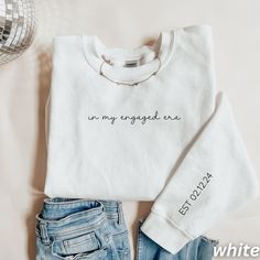 a white sweater with the words in my engaged era written on it next to jeans