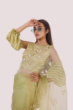 The stylish green organza saree with cold-shoulder balloon-sleeved blouse, embroidered with cut dana, off-white stripes blouse. Shop designer saris online in the USA from Pure Elegance. Disclaimer: The actual product may vary slightly from the image. These are custom orders, hence expect slight variation in color and placement of the motif or buta. ESTIMATED DELIVERYBecause this is a custom order, it would take about 4 weeks from the date of purchase. RETURN POLICYThis product is a custom order and cannot be returned or exchanged. Festive Organza Blouse With Dupatta, Green Tissue Silk Blouse With Dupatta, Eid Organza Blouse With Cutdana Details, Eid Organza Blouse With Cutdana, Eid Cutdana Organza Blouse, Festive Green Sets With Embroidered Sleeves, Festive Green Set With Embroidered Sleeves, Designer Organza Blouse With Resham Embroidery, Designer Wear Pre-draped Organza Saree For Eid