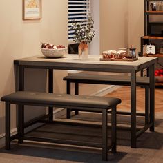 a kitchen table with two benches and a bowl of fruit on the counter next to it