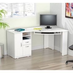 a corner desk with a computer monitor and keyboard on it in front of a window