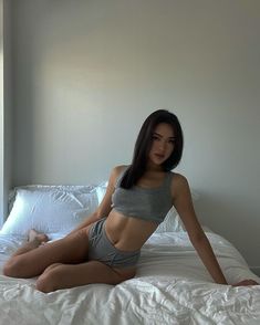 a woman is sitting on a bed posing for the camera