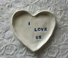 a heart shaped dish with the words i love us written in blue ink on it