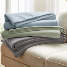 four folded sheets sitting on top of a couch