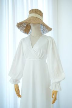 a mannequin wearing a white dress and large straw hat with tassels