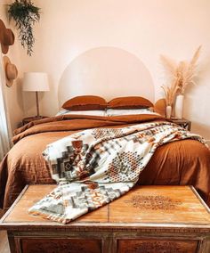 a bed sitting in a bedroom next to a wooden table with a blanket on top of it