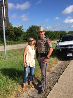 a police officer standing next to a woman in front of a street sign and car