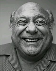 black and white photograph of an older man smiling at the camera with his eyes wide open