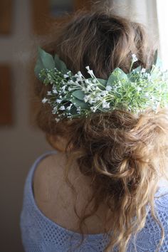 a woman wearing a flower crown in front of a window with greenery on her head