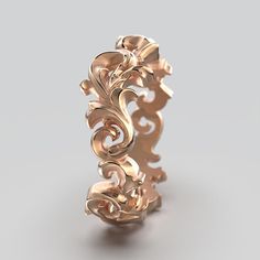 an intricately designed gold ring on a gray background