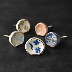 four different types of ceramic knobs on a black surface with gold and blue designs