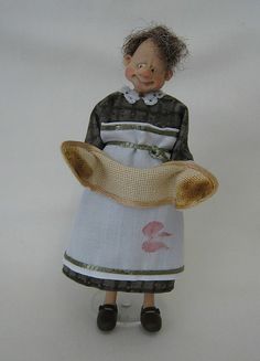 a doll is wearing a dress and holding a hat