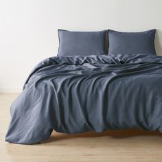 a bed with blue sheets and pillows on top of it in a room next to a wall