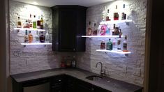 a kitchen with white brick walls and shelves filled with liquor bottles on the back wall