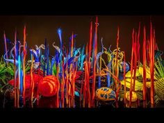 colorful glass sculptures are displayed in front of a black background with red, yellow and blue sticks