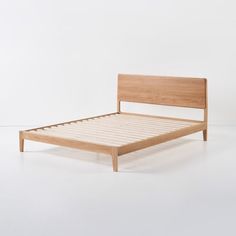 a bed with wooden slats and no headboard is shown in front of a white wall