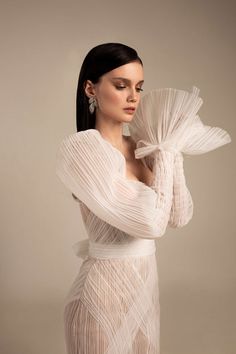 a woman in a white dress is posing with her arms wrapped around her neck and hands behind her head