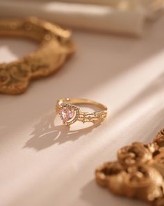 two gold rings sitting next to each other on a white tablecloth with ornate designs