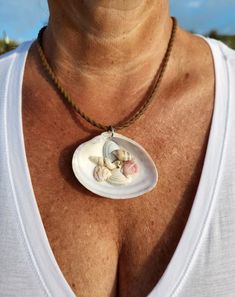 a woman wearing a necklace with seashells on it