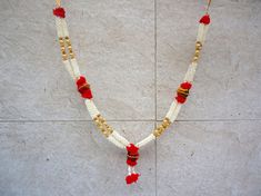 a white and red beaded necklace with gold accents