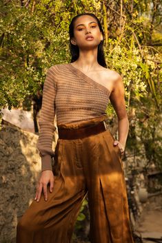 a woman standing in front of a tree with her hands on her hips and looking off to the side