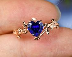 a close up of a person's hand holding a ring with a blue stone