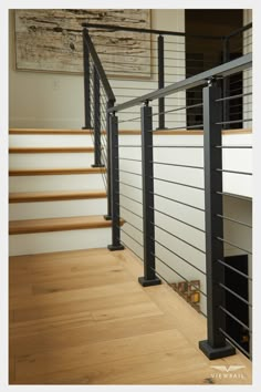 an image of a stair railing in the living room with wood floors and white walls