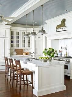 a large kitchen with white cabinets and wooden flooring, along with an island in the middle