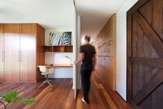 a woman is walking up the stairs to her home office with wood paneling and sliding doors