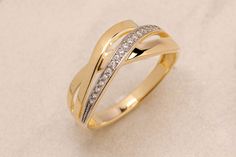 a yellow gold ring with diamonds on the inside and outside, sitting on a white surface