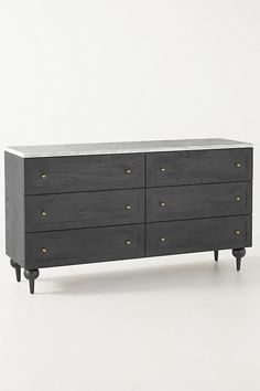 a black dresser with gold knobs on the top and bottom drawers, against a white background