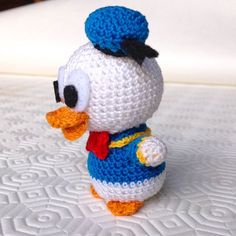 a crocheted toy duck wearing a blue and white outfit