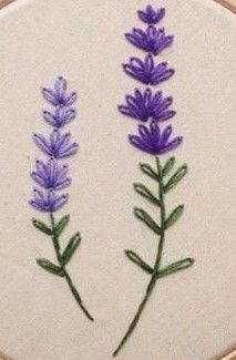 two purple flowers are embroidered onto a white hoop